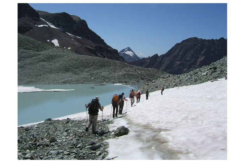 grupo de montañerosavanzando por la nieve a lo largo del lago